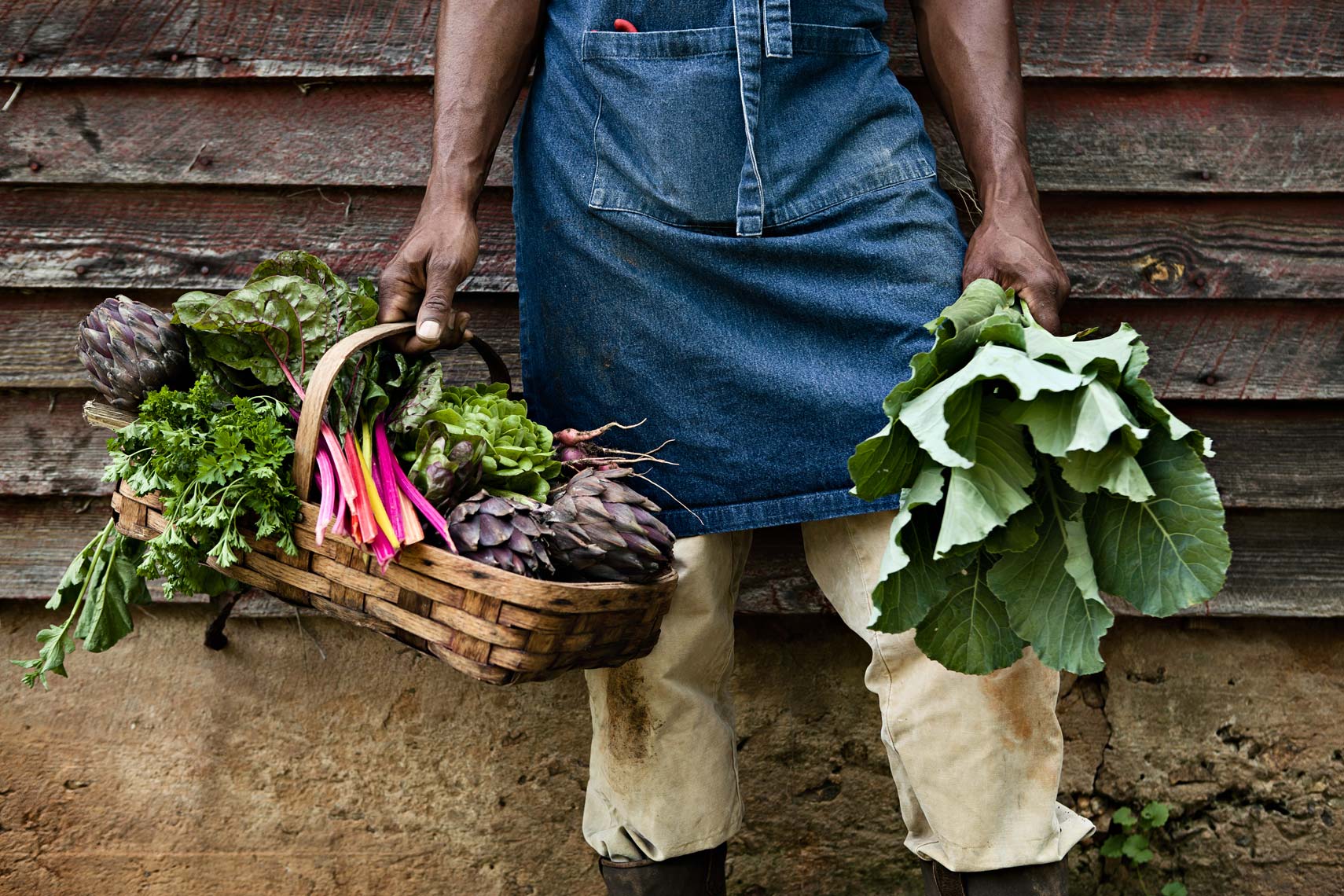Lifestyle portrait of African American farmer holding basket of vegetables, Atlanta