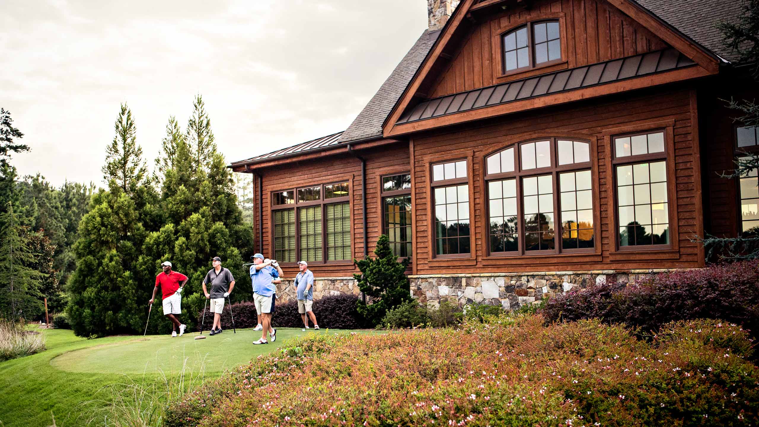 Group of men tee-off on golf course next to clubhouse, Atlanta