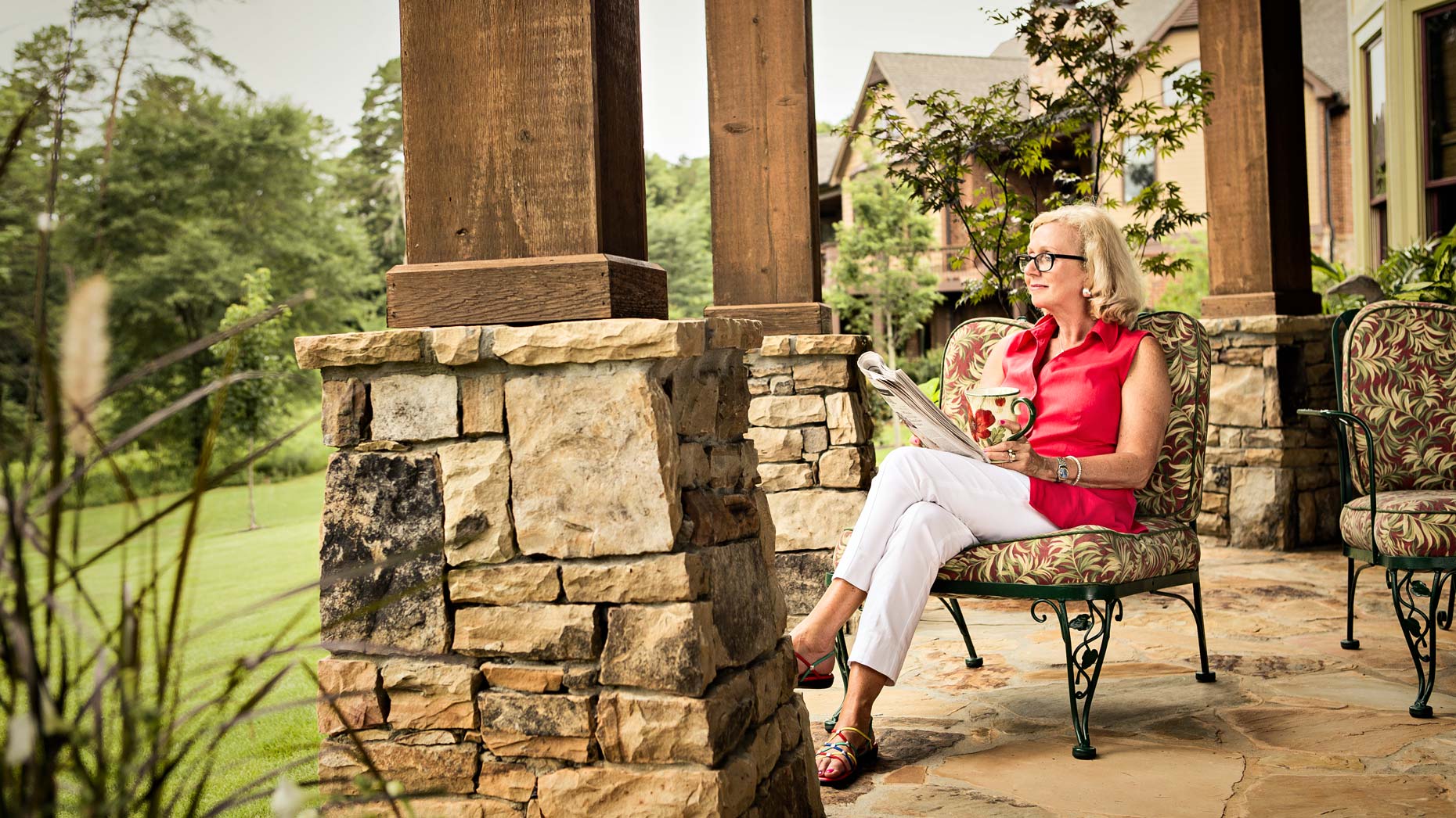 Senior woman sits on her patio looking out at garden, Atlanta